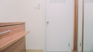 A room with a wooden bench, a white door with a metal handle, and a wall-mounted hook system.