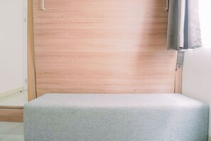 Guest room features a light floor, a bench, and a window with a curtain.