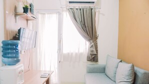 A room with a water dispenser, a table, a sofa, and a window with curtains.