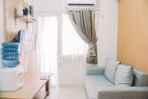 Relax in this serene space with a sofa against the wall, a water dispenser, and a window with sheer curtains.
