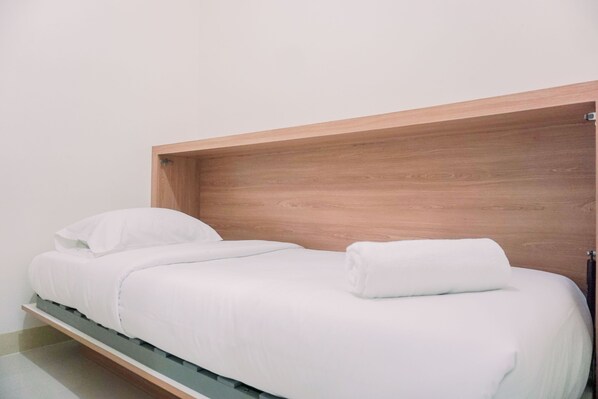 Simple, minimalist room with a single bed and a clean aesthetic.