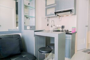 A compact kitchenette with a built-in stove, a sink, and a small bar area with stools. - Best Deal And Restful 2Br Green Pramuka City Apartment (Jakarta)
