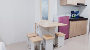 A small kitchenette with a wooden table, three stools, a refrigerator, and a sink. - Good Deal And Homey Studio Apartment Anwa Residence Bintaro (South Tangerang)