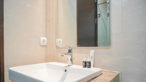 A bathroom with a white sink, a mirror, and two toiletries on the counter.