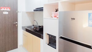 Une cuisine compacte équipée d’un évier, d’un plan de travail noir, d’un réfrigérateur en acier inoxydable et d’une porte en bois.