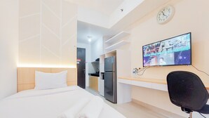 Une chambre d’hôtel équipée d’un lit, d’un bureau, d’une chaise, d’une télévision et d’un coin cuisine.