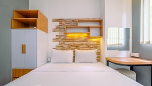 A hotel room with a bed, a wardrobe, a desk, and a wall-mounted shelf unit. - Best And Stylish 2Br At Signature Park Grande Apartment (Jakarta)