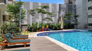 Relax by the pool surrounded by lounge chairs and a children's play area.