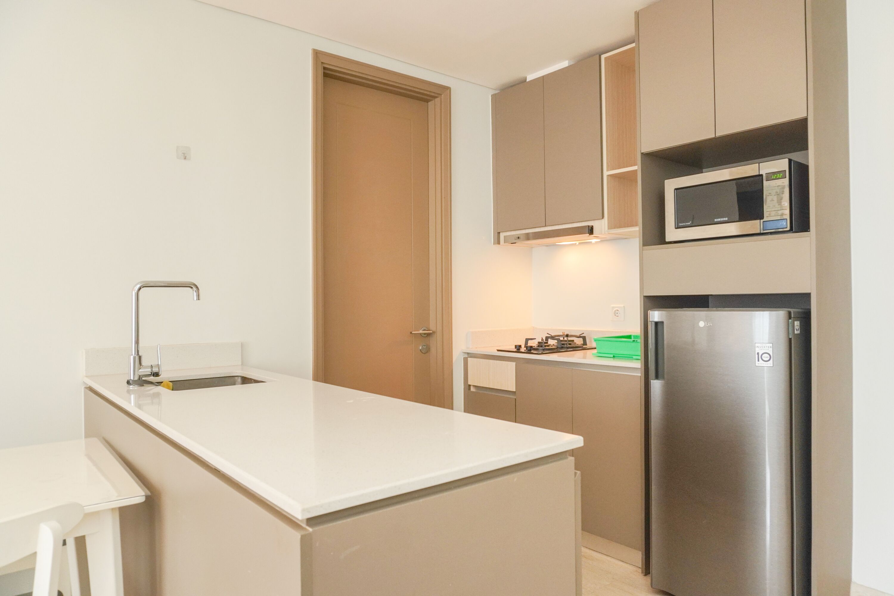 A modern kitchen with a white countertop, stainless steel appliances, and beige cabinetry.