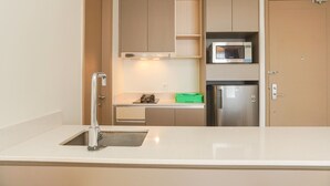 A compact kitchen with a sink, a microwave, and a refrigerator. - Modern Look And Nice 2Br Gold Coast Apartment Near Pik (Jakarta)