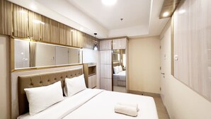A hotel room with a large bed, a mirror, and a wardrobe. - Good Deal And Homey 1Br Tamansari Skylounge Makassar Apartment (Makassar)