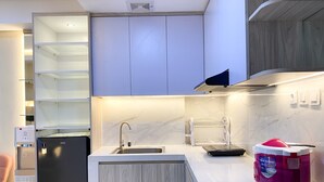 A modern kitchen with a built-in dishwasher, a rice cooker, and a wine cooler. - Good And Modern 2Br Daan Mogot City Apartment (Jakarta)