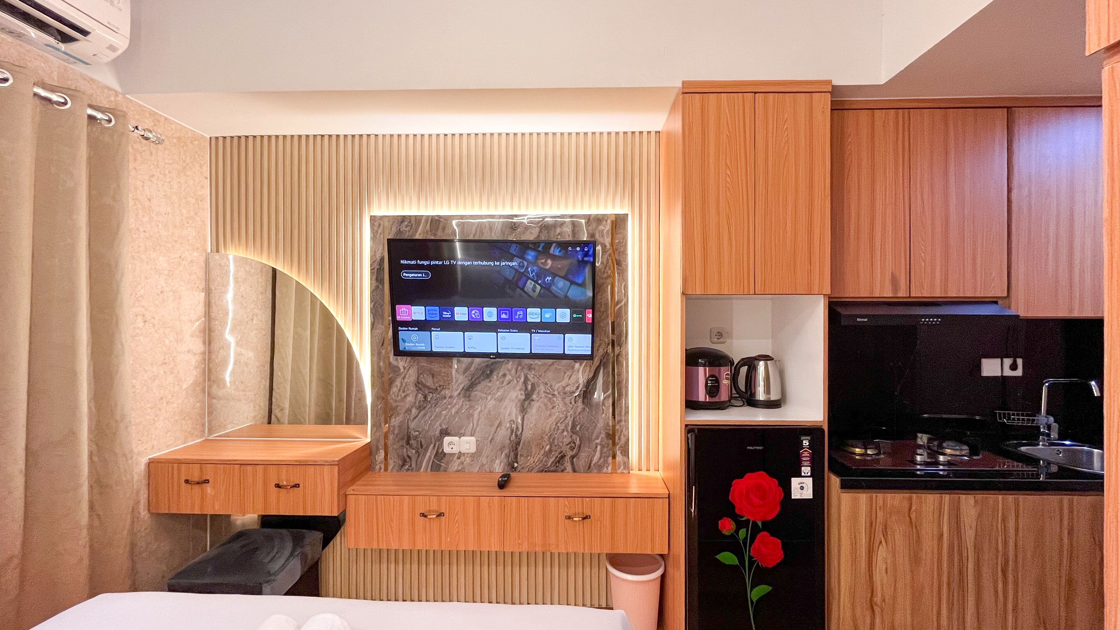 Une chambre d’hôtel moderne dotée d’une télévision intégrée, de meubles en bois, d’une petite kitchenette et d’un mur décoratif en marbre.