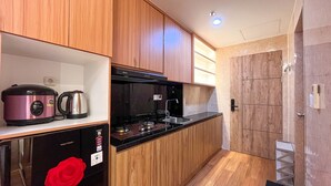A compact kitchen with wooden cabinets, a black countertop, a gas stove, and a coffee maker.