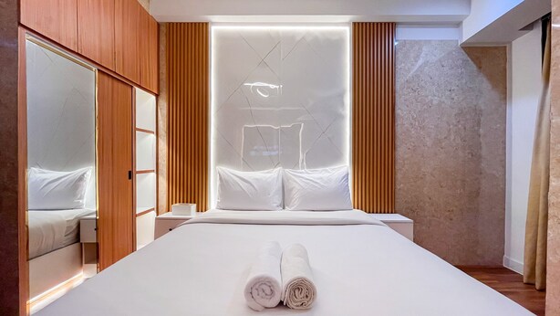 A modern hotel room with a large bed, wooden paneling, and a large mirror.