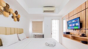 A hotel room with a bed, a TV mounted on the wall, and a window with curtains.
