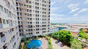 A high-rise building with multiple balconies, a rooftop pool, and a landscaped courtyard with a swimming pool.