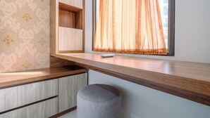 A modern room with a built-in desk, a small stool, and a window with sheer curtains. - Good Deal And Relaxing 2Br Transpark Cibubur Apartment (Depok)