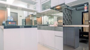 A modern kitchen with white cabinets, granite countertops, and a built-in oven. There is a refrigerator and a coffee machine on the counter. - Good Deal And Relaxing 2Br Transpark Cibubur Apartment (Depok)
