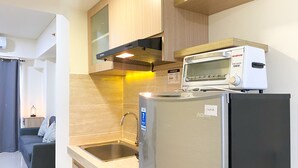 A modern kitchen with a built-in oven, microwave, and refrigerator. - Best Spacious And Homey 2Br At Meikarta Apartment (Cikarang)