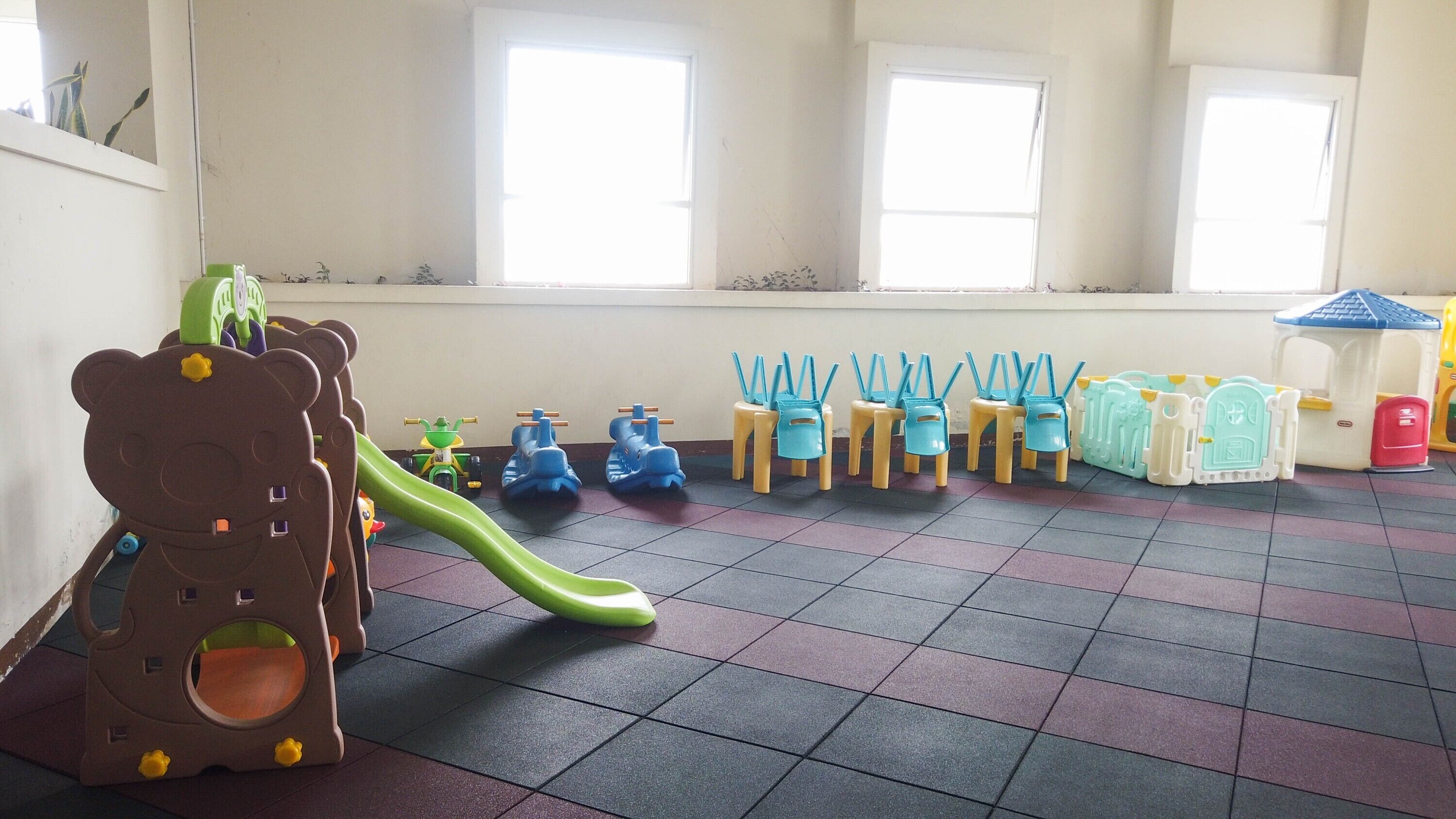 A play area with a slide, small chairs, and a playhouse.