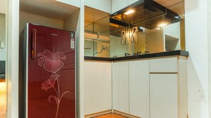 A compact kitchen with white cabinets, a red refrigerator with a floral design, and a black countertop. - Good Deal And Comfortable 1Br The Boulevard Apartment (Jakarta)
