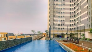 Ein Schwimmbecken mit Blick auf einen Hochhaus im Hintergrund.