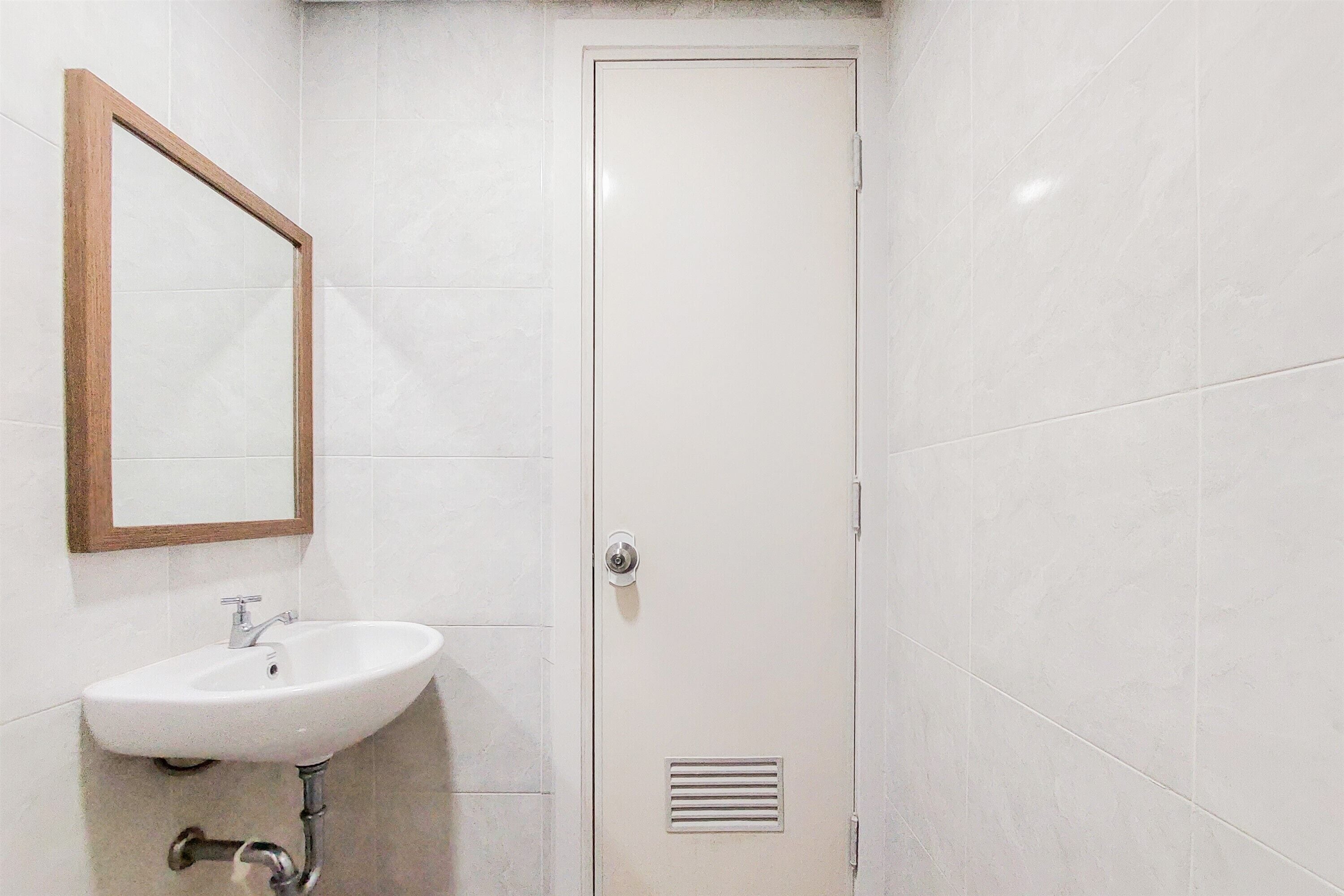 A bathroom with a white sink, a mirror, and a door.