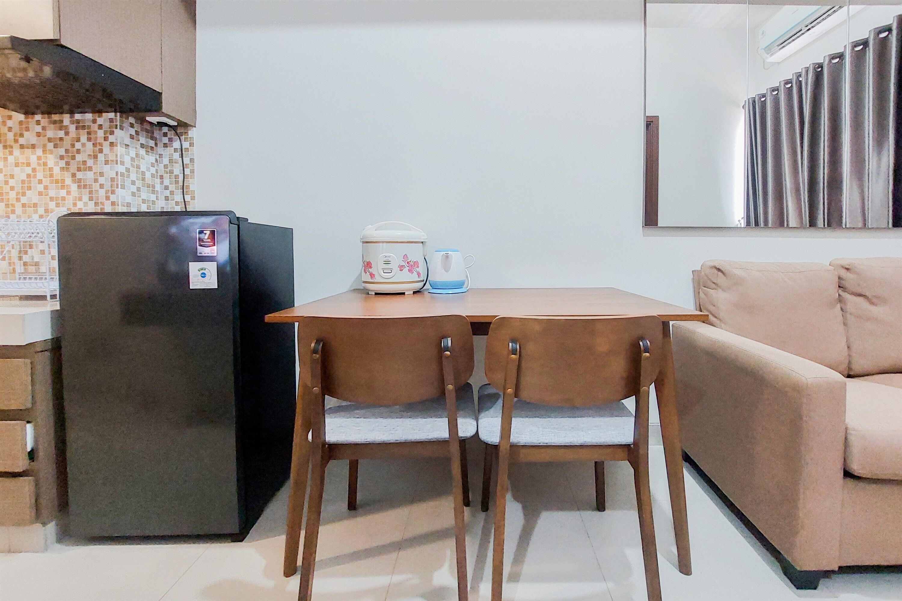A compact kitchen with a refrigerator, a coffee maker, and a dining table with chairs.