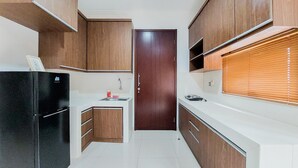 Eine moderne Küche mit Holzausstattung, einem schwarzen Kühlschrank und einem Fenster mit Jalousien.