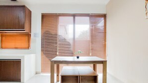 Ein Zimmer mit Holztisch, Bank, einer Topfpflanze und einer Holztür mit Jalousien.