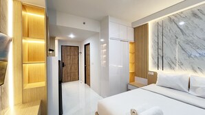 A modern hotel room with a large bed, wooden paneling, and marble accents.