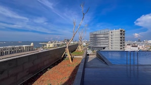 A rooftop pool with a view of the cityscape, including modern buildings and a body of water.