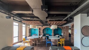 A modern interior with round tables and chairs, wooden benches, and a blue accent wall.