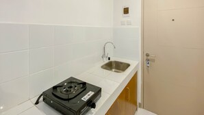 A kitchen with white tiles, a sink, a stove, and a door with a lock. - Brand New Studio For 4 Pax At Tokyo Riverside Pik 2 Apartment (Teluknaga)