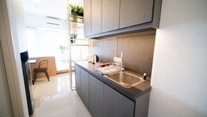 A modern kitchen with grey cabinets, a stainless steel sink, and a built-in plant shelf. - Homey Studio At Orchard Supermall Mansion Apartment (Surabaya)