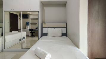 A hotel room with a bed, a desk, a chair, and a wardrobe.