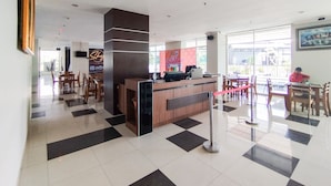 A hotel lobby with a reception desk, check-in counters, and a seating area with tables and chairs. - Strategic And Comfy Studio At Skyland City Jatinangor Apartment (Hegarmanah)