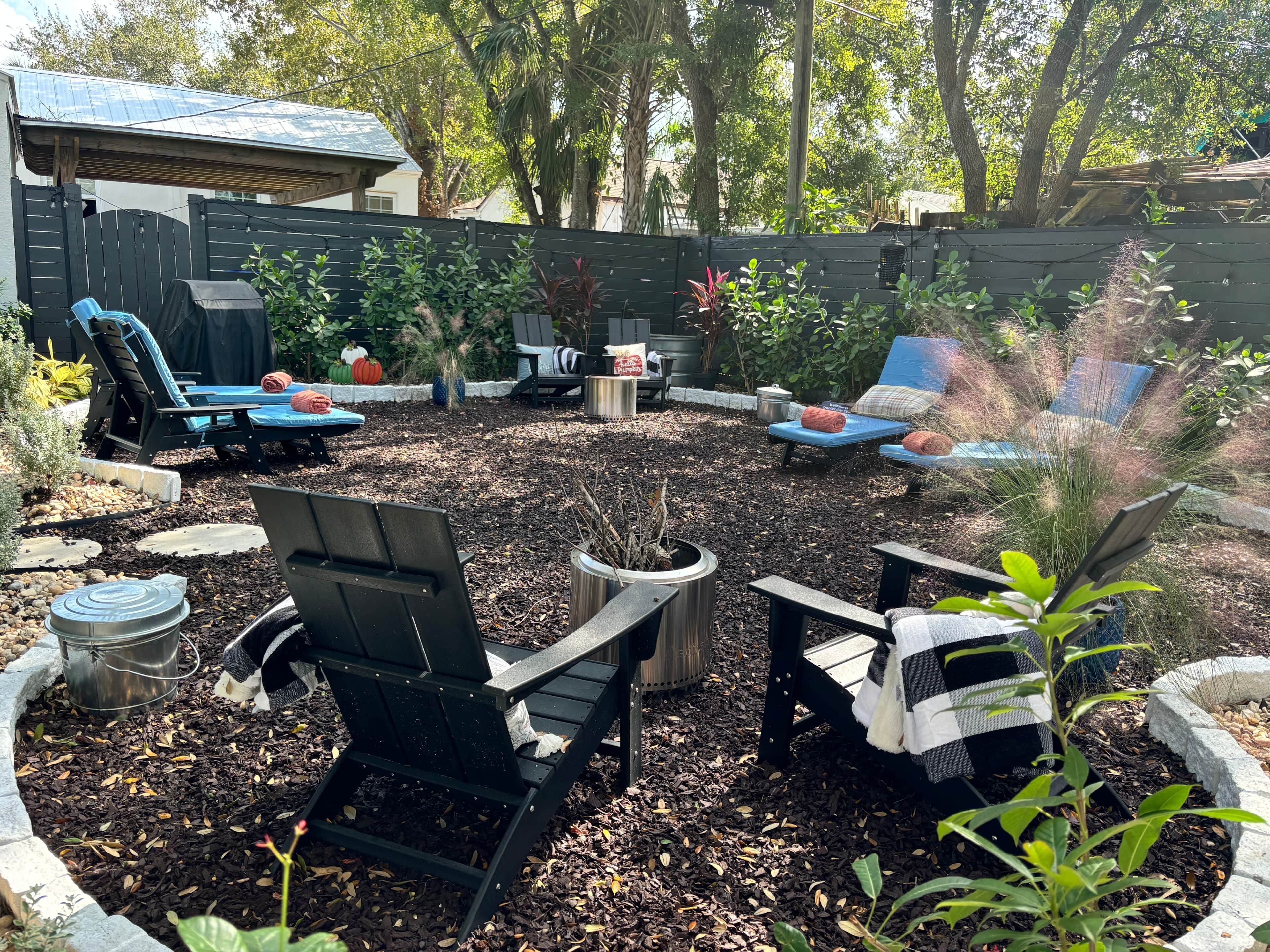 Patio trasero con mobiliario exterior, una chimenea y una zona ajardinada.