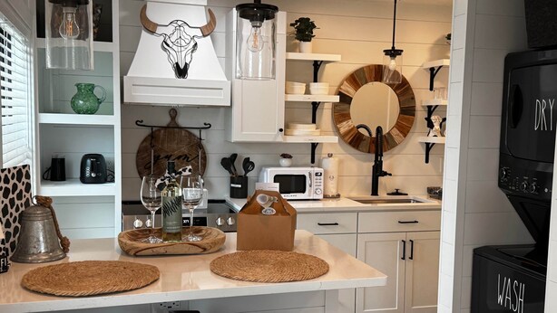 A modern kitchen with white cabinetry, a black microwave, and a black dishwasher. - Black Brindle Cottage, Downtown Ft. Myers: Walk to Best Eats and Shops! (Fort Myers)