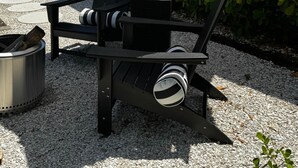 A patio with a patterned umbrella, a chair, a small table, and a trash can. - Black Brindle Cottage, Downtown Ft. Myers: Walk to Best Eats and Shops! (Fort Myers)