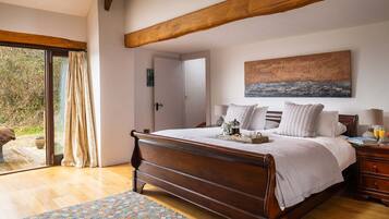 A bedroom with a wooden bed, a large window, and a view of greenery outside.