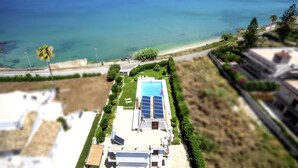 Une propriété résidentielle dotée d’une piscine, de panneaux solaires et offrant une vue sur la mer.