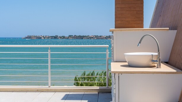 Un balcon avec un évier blanc et une vue sur la mer.
