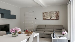 Ein modernes Wohnzimmer mit grauem Sofa, weißem Couchtisch und einem Bild an der Wand.