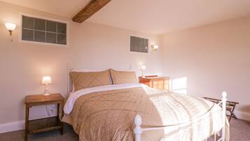 A bedroom with a bed, two bedside tables, a wooden headboard, a window, and wall-mounted lights.