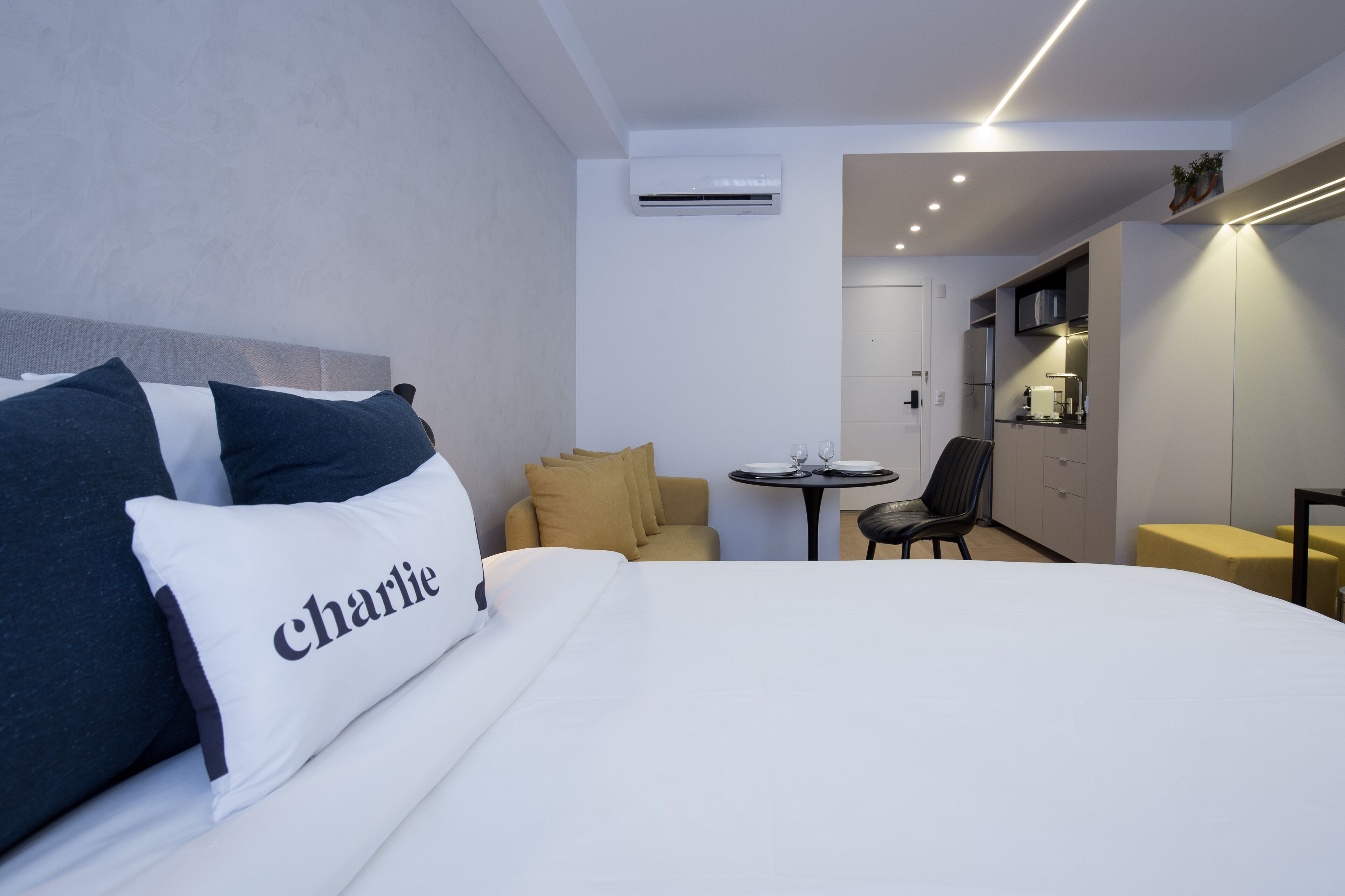 A hotel room with a bed, a small table, a sofa, and a kitchenette.