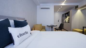 A hotel room with a bed, a small table, a sofa, and a kitchenette.