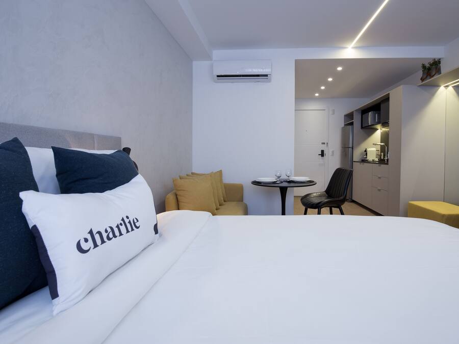 A hotel room with a bed, a small table, a sofa, and a kitchenette.