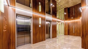 Un área de ascensor moderna con paneles de madera y un piso de baldosas pulidas.